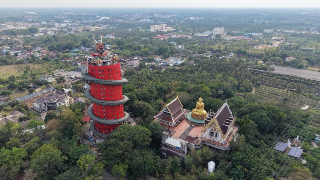 Aerial view of Wat Samphran Dragon Temple surrounded by greenery and nearby buildings in Thailand