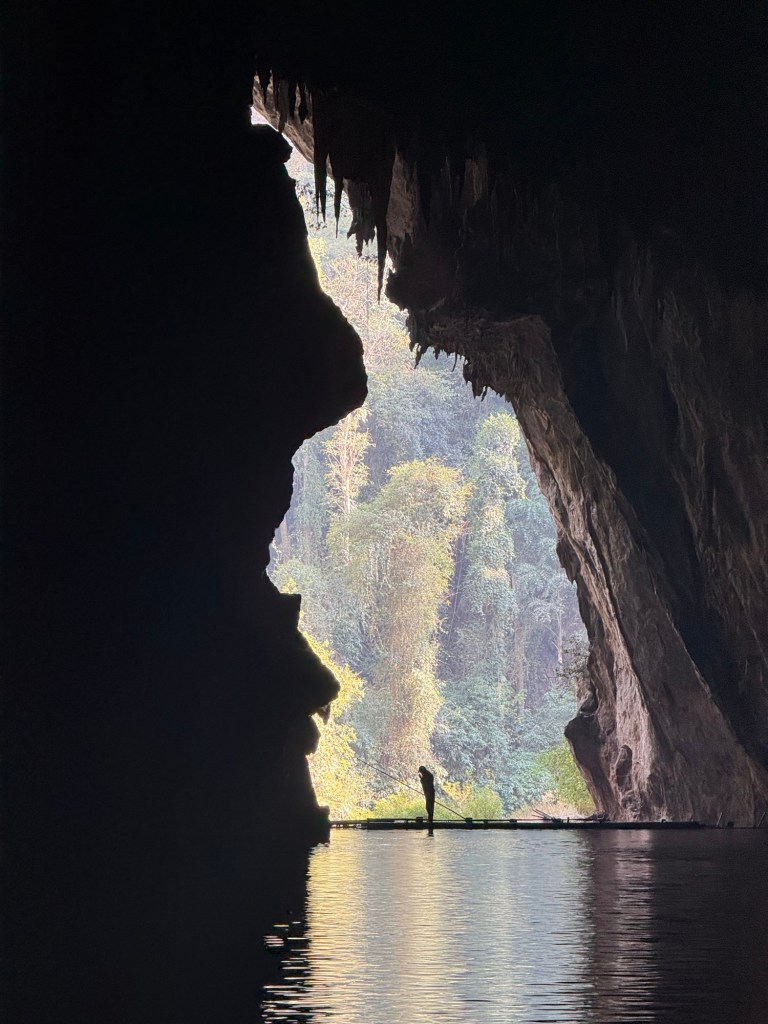 View from inside Tham Lod Cave near Pai, Thailand looking toward the cave opening with daylight reflecting on the underground river.