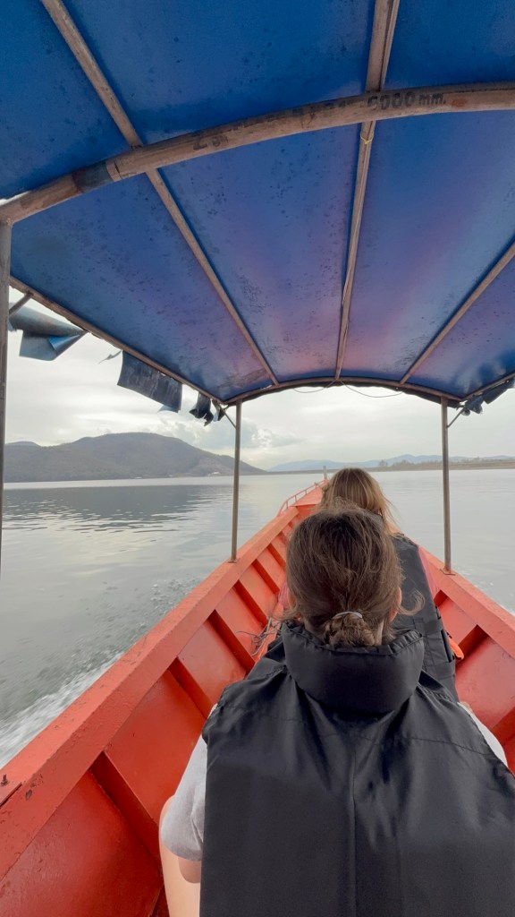 Longtail boat ride across Mae Ngat Dam in Sri Lanna National Park, Chiang Mai with children looking out over calm water and mountain views