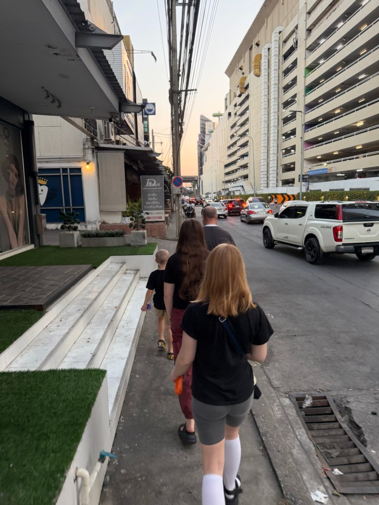 Family walking along a neighborhood street in Bangkok during slow travel
