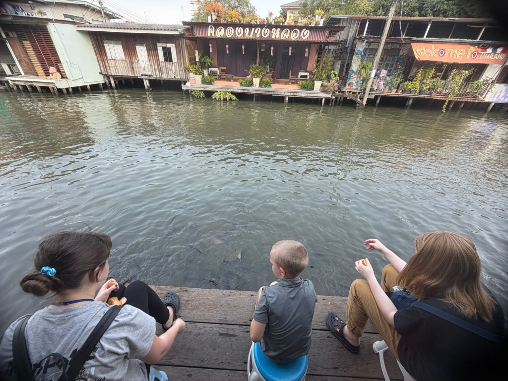 Children feeding fish along a canal in Thonburi Bangkok