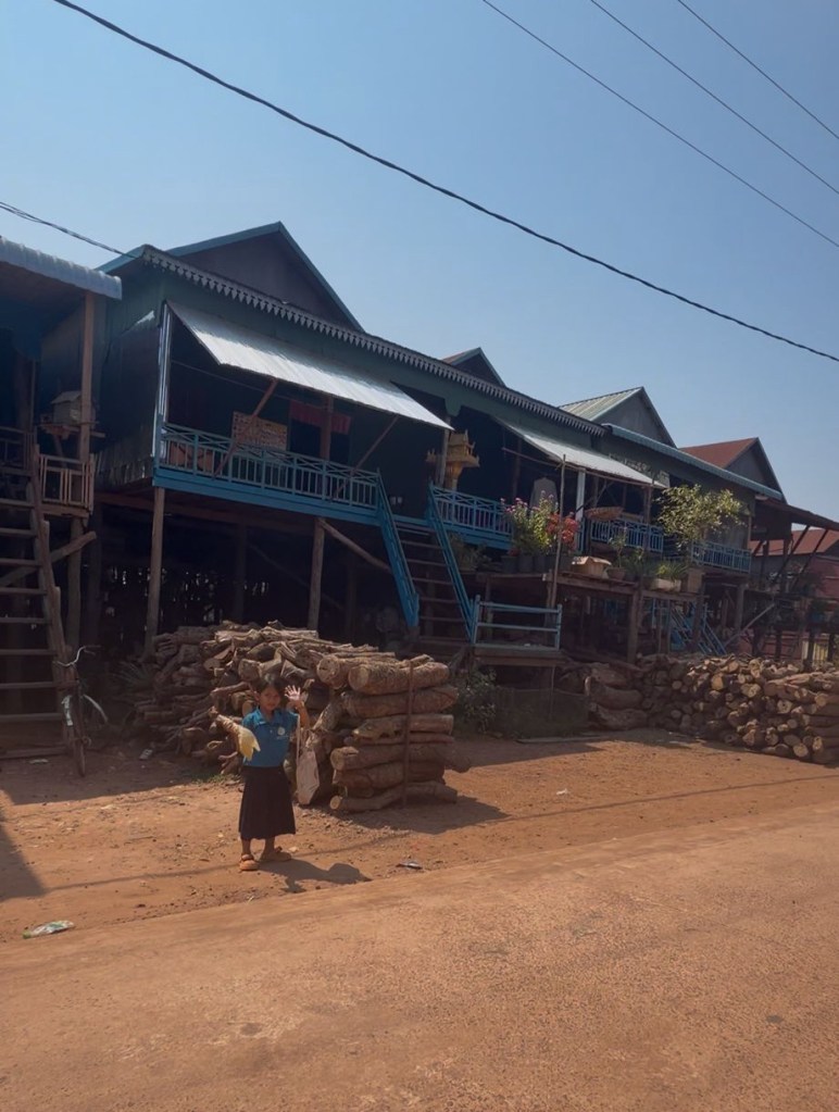 Child waving from village near Tonlé Sap Lake in Cambodia