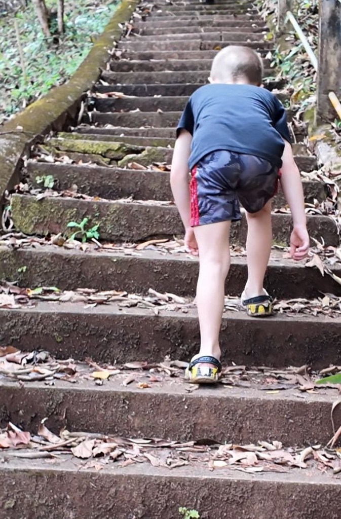 Child climbing steep steps in Thailand during family travel