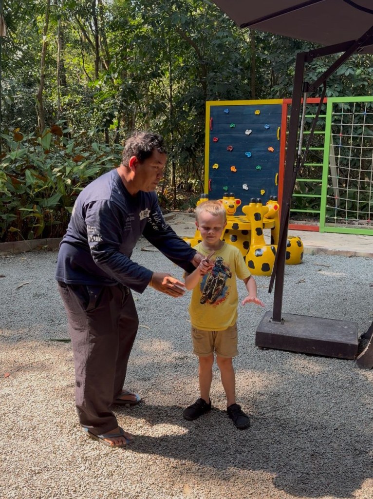 Man showing young boy how to spin helicopter seed pods in Siem Reap Cambodia