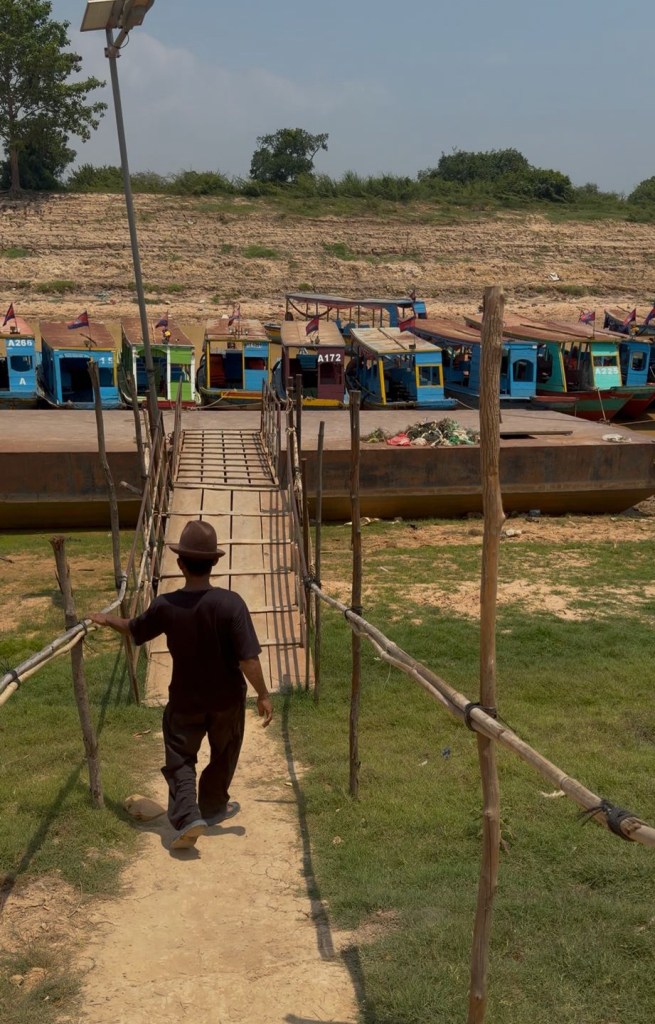 Man walking toward boats at Tonlé Sap Lake during dry season in Cambodia