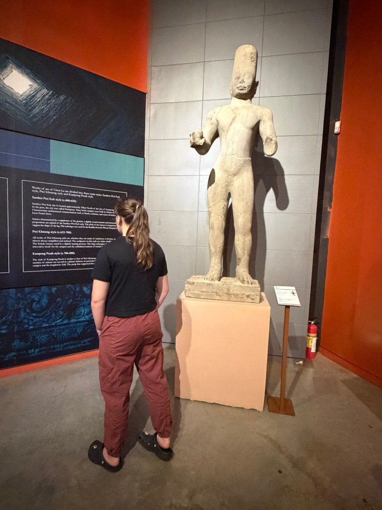 Teen girl looking at ancient statue inside Angkor Museum in Siem Reap Cambodia