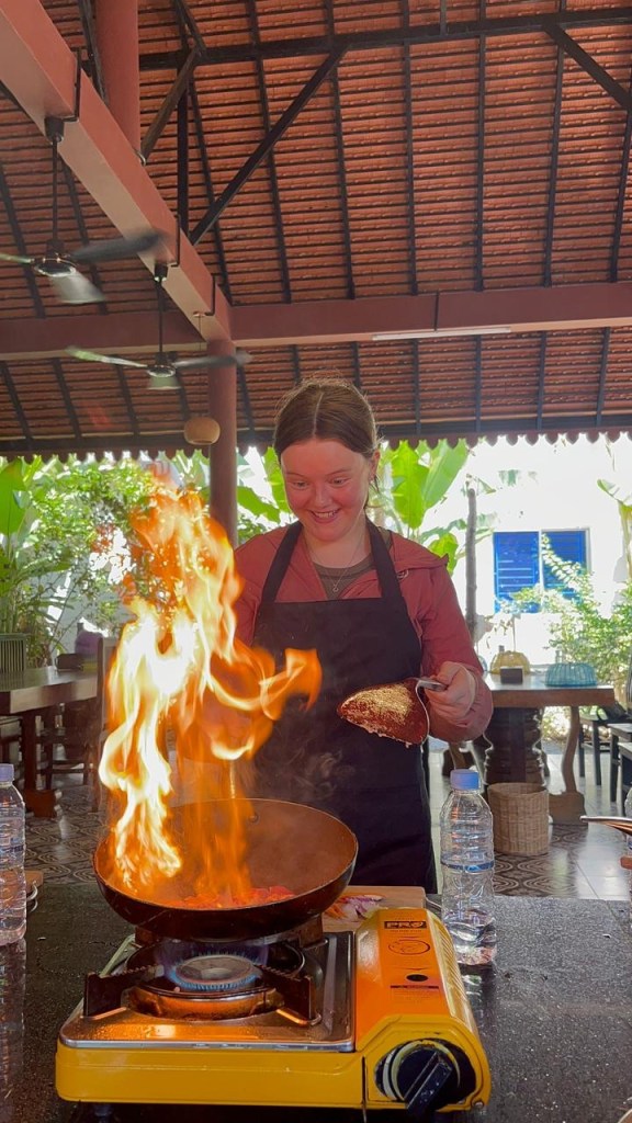 Teen girl cooking over open flame during Khmer cooking class in Siem Reap Cambodia