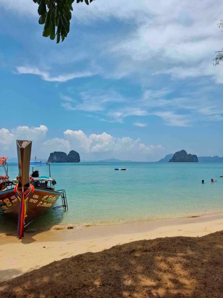 Longtail boat parked beside a tropical beach near Emerald Cave and Koh Mook in Thailand.