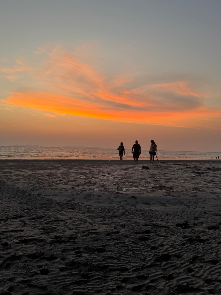 Family walking along the beach at sunset in Koh Lanta, Thailand.