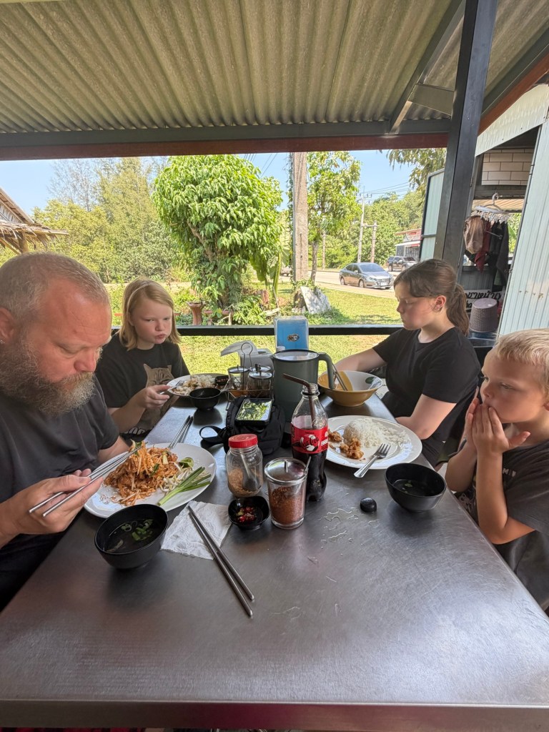 Family eating Thai food at a small roadside restaurant in Koh Lanta, Thailand during a long-term family stay.