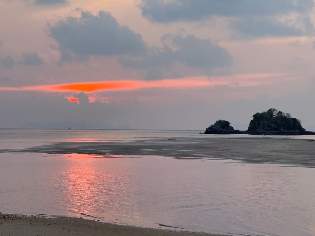 Sunset over the ocean in Koh Lanta with calm water and soft pink clouds at dusk.